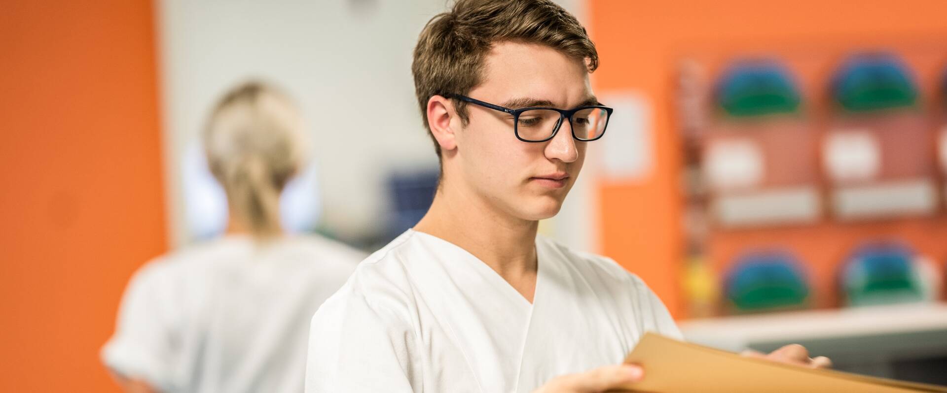 Junger Pfleger mit Brille ordnet Dokumente